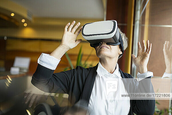 Female entrepreneur gesturing while using virtual reality simulator at hotel