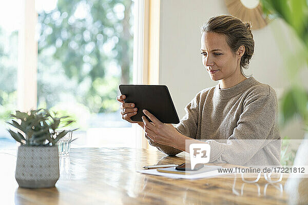 Geschäftsfrau  die ein Tablet benutzt  während sie am Tisch sitzt