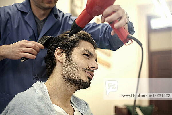 Friseur föhnt das Haar eines männlichen Kunden