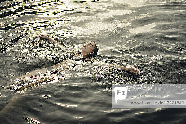 Junge Frau schwimmt im Wasser und entspannt sich im Sommer
