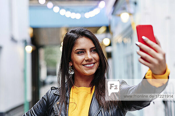 Schöne Frau lächelnd während der Aufnahme selfie auf Handy in der Stadt