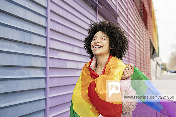 Cheerful woman wrapped in rainbow flag