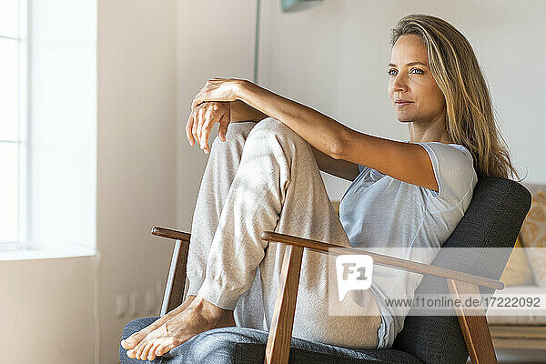 Frau in bequemer Loungewear entspannt sich auf einem Sessel im Wohnzimmer