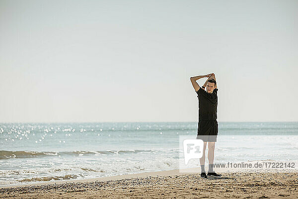 Junger Mann streckt die Hände aus  während er am Strand steht