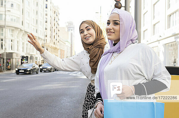 Arab women hailing taxi while standing in city