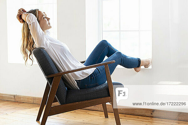 Frau mit geschlossenen Augen entspannt auf einem Stuhl zu Hause