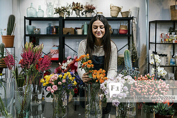 Junge Blumenhändlerin arrangiert Blumen im Geschäft