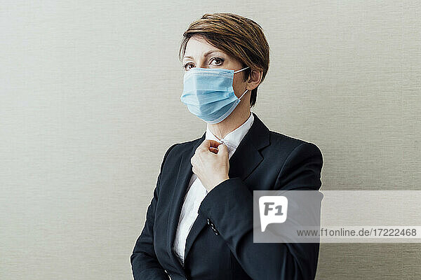 Weiblicher Geschäftsmann mit Gesichtsschutzmaske vor einer Wand während COVID-19
