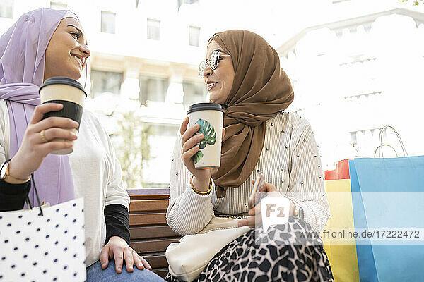 Arabische Freundinnen trinken Kaffee und sitzen auf einer Bank