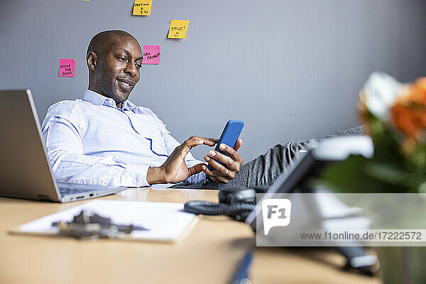 Male entrepreneur using smart phone at desk in office