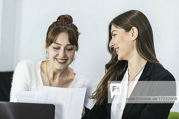 Unternehmer lächelnd bei der Papierkontrolle im Büro