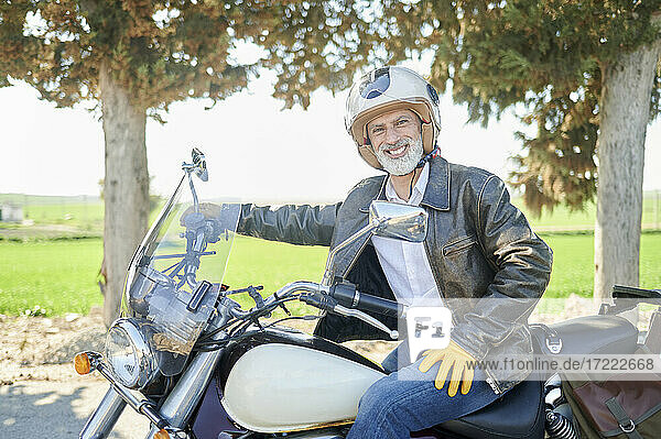 Lächelnder reifer Mann  der einen Helm trägt und auf einem Fahrrad sitzt