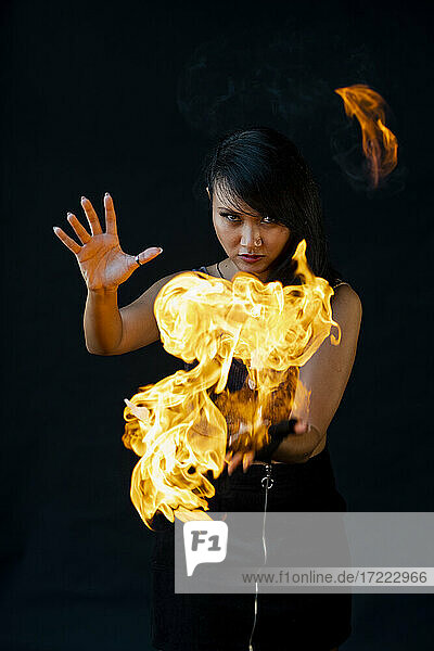 Weibliche Feuertänzerin mit Feuer vor schwarzem Hintergrund