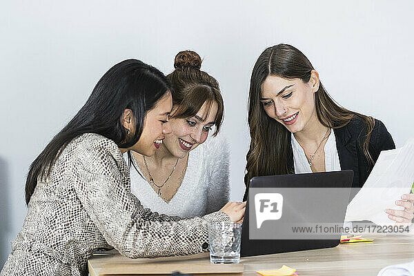 Lächelnde Unternehmerinnen arbeiten am Laptop im Büro