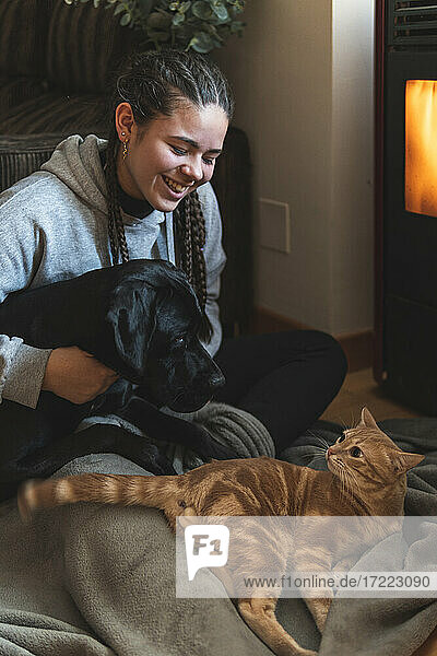 Lächelnder weiblicher Teenager sitzt mit Haustieren zu Hause