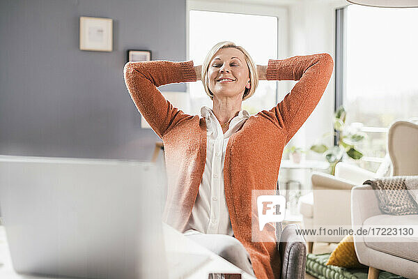 Relaxed female entrepreneur with hands behind head in home office