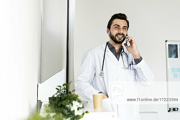 Smiling male healthcare talking on smart phone while looking away