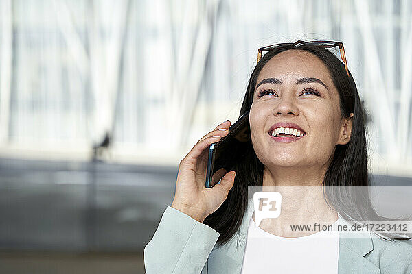 Cheerful businesswoman looking up while talking on phone