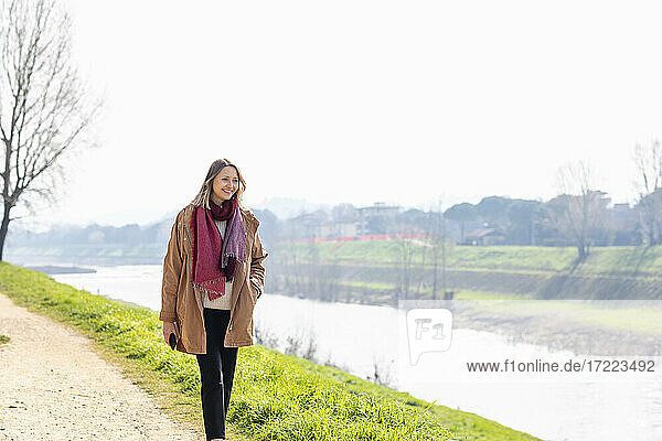 Lächelnde Frau  die am Flussufer spazieren geht