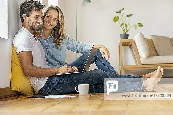 Mid adult man using laptop while sitting with girlfriend at home office