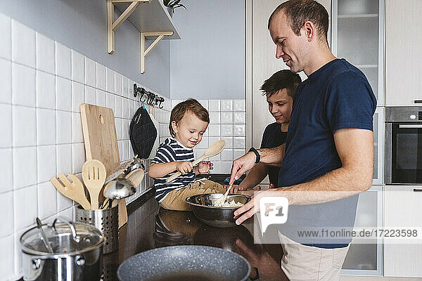 Father with cute sons preparing food in kitchen at home