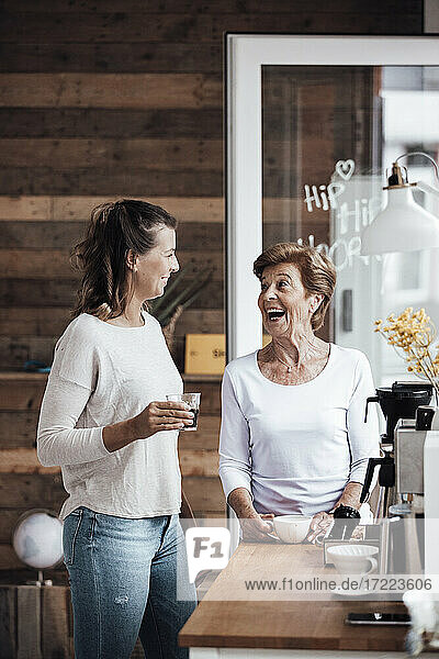 Glückliche ältere Frau im Gespräch mit ihrer Enkelin bei einem Kaffee zu Hause