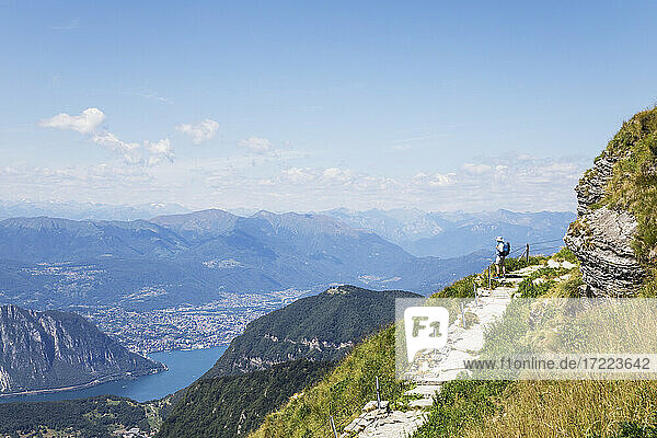 Älterer Wanderer bewundert die umliegende Landschaft vom Wanderweg auf dem Gipfel des Monte Generoso