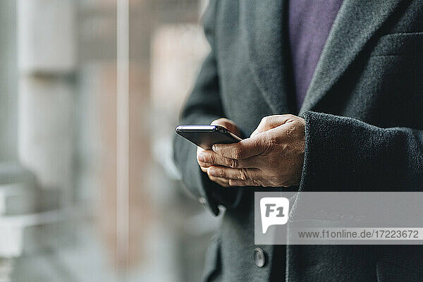 Mann in Jacke mit Smartphone