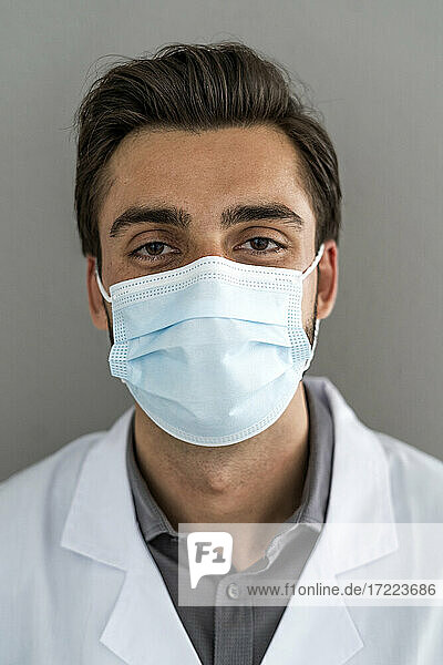 Männlicher Mitarbeiter des Gesundheitswesens trägt bei COVID-19 eine Schutzmaske