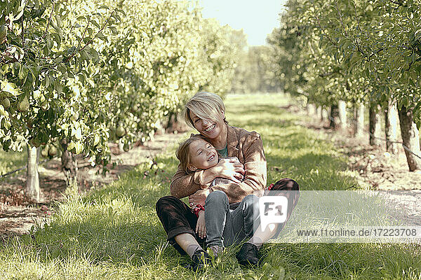 Smiling mother and daughter relaxing at orchard