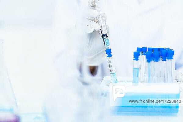 Forscher beim Einspritzen einer Flüssigkeit in ein Reagenzglas im Labor