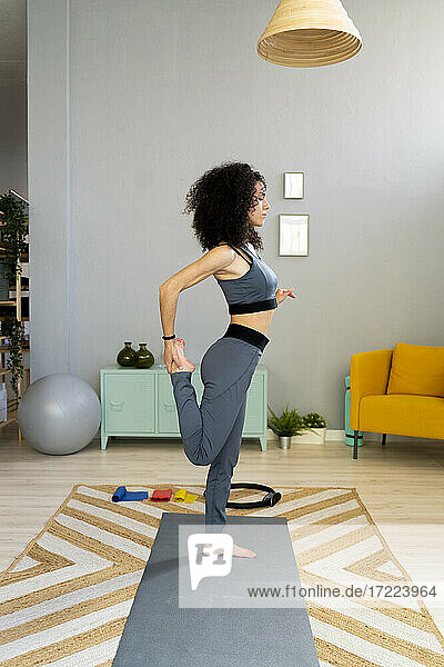 Frau übt Yoga auf einem Bein zu Hause