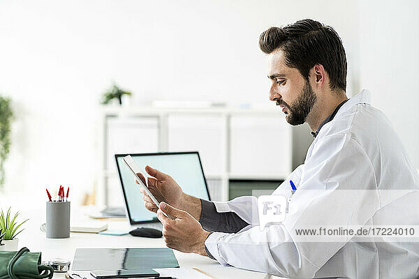 Male healthcare worker using digital tablet while sitting at desk