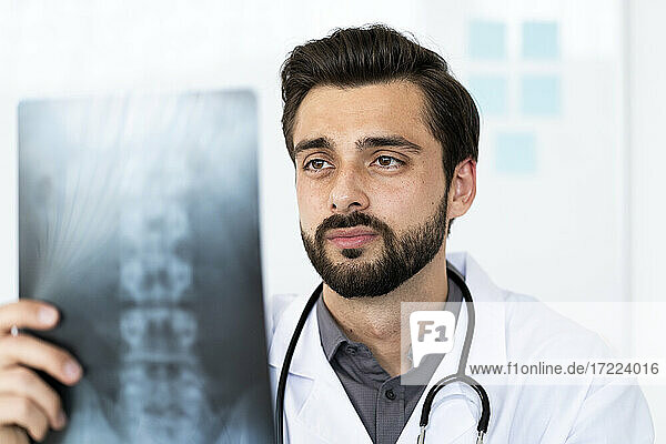 Gutaussehender medizinischer Angestellter bei der Analyse von Röntgenbildern im Krankenhaus