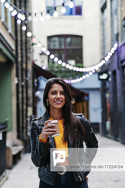 Schöne Frau mit Einweg-Kaffeebecher steht auf der Straße in der Stadt