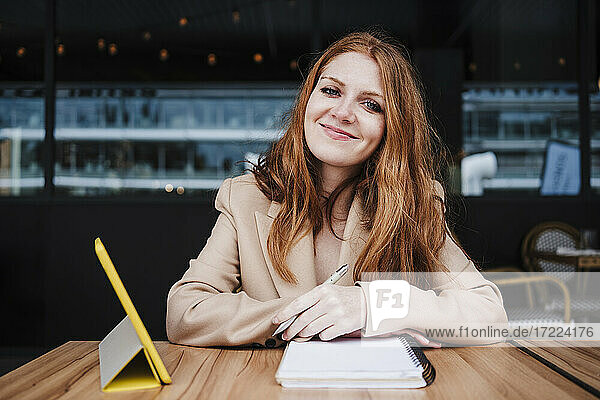 Lächelnde schöne Frau mit Tagebuch sitzt am Tisch in einem Cafe