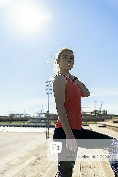 Young female athlete standing on pier during sunny day