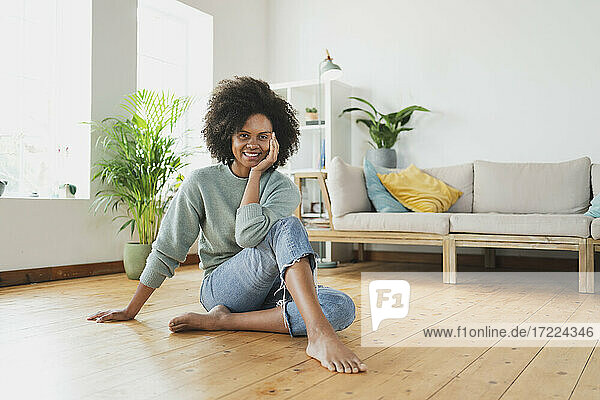 Lächelnde Frau sitzt zu Hause auf dem Boden