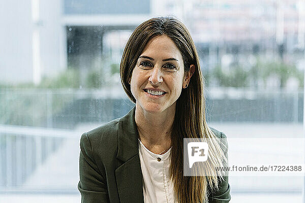 Businesswoman in smart casual by glass wall at office
