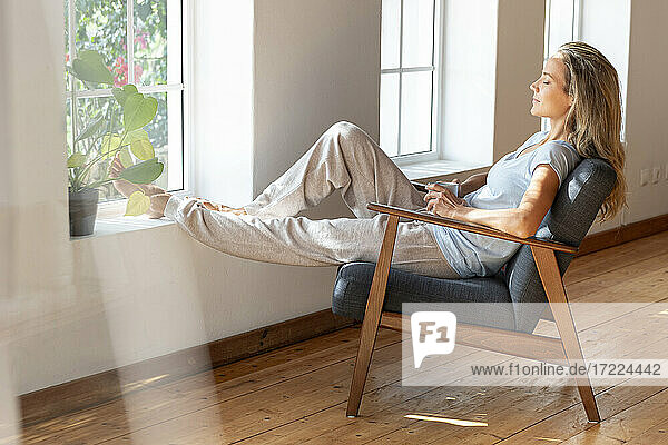 Frau mit Kaffeetasse entspannt sich auf einem Stuhl zu Hause