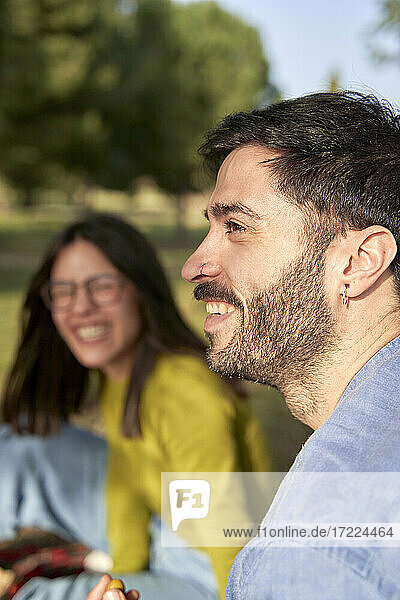 Lächelnder Hipster-Mann schaut weg  während er ein Picknick mit seiner Freundin genießt