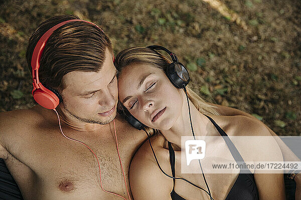 Junges Paar liegt im Gras und hört Musik mit Kopfhörern