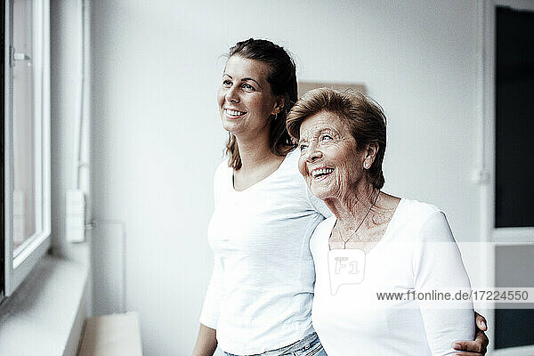 Fröhliche ältere Frau mit Enkelin  die zu Hause wegschaut