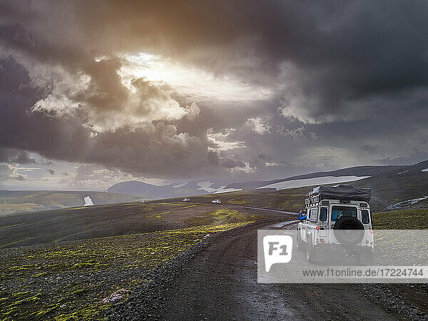 Dramatic sky over off-road car driving along remote dirt road at Fjallabak Nature Reserve