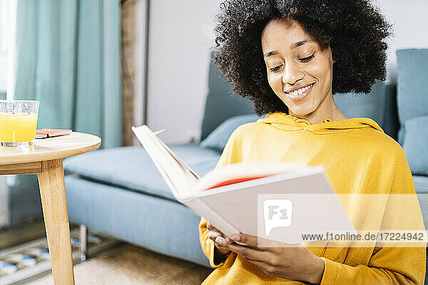 Junge Frau liest ein Buch  während sie zu Hause sitzt