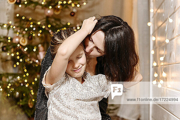 Mutter küsst Tochter zu Hause während Weihnachten