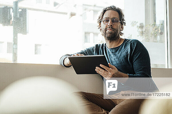 Mann mit digitalem Tablet in einem Café sitzend