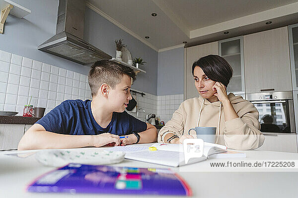Mutter und Sohn schauen sich beim Lernen in der Küche zu Hause an
