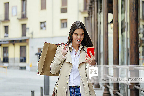 Junge Frau schaut beim Einkaufen in der Stadt auf ihr Smartphone