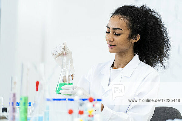 Forscherin beim Pipettieren von Flüssigkeit in einen Kolben während der Arbeit im Labor